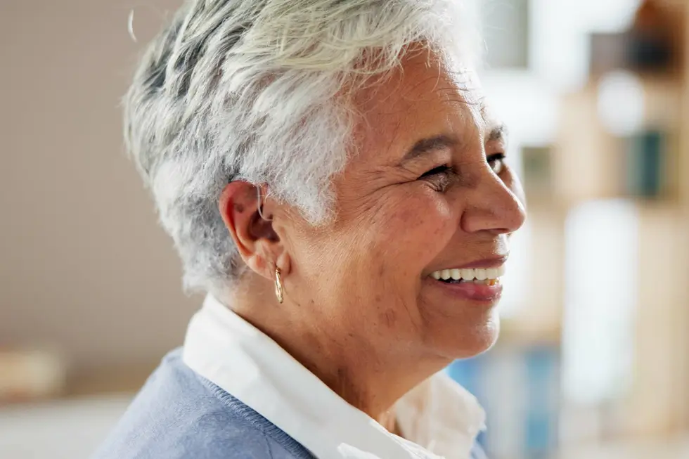 Seniorin mit grauen Haaren und Hörgerät im Ohr, seitliche Ansicht