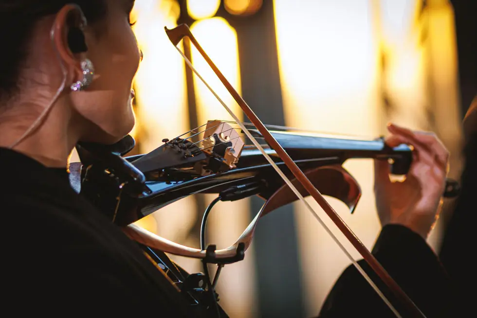 Violinistin mit In-Ear-Monitoring spielt Geige im Nahaufnahme mit Bogen und Instrumentenkinnhalter